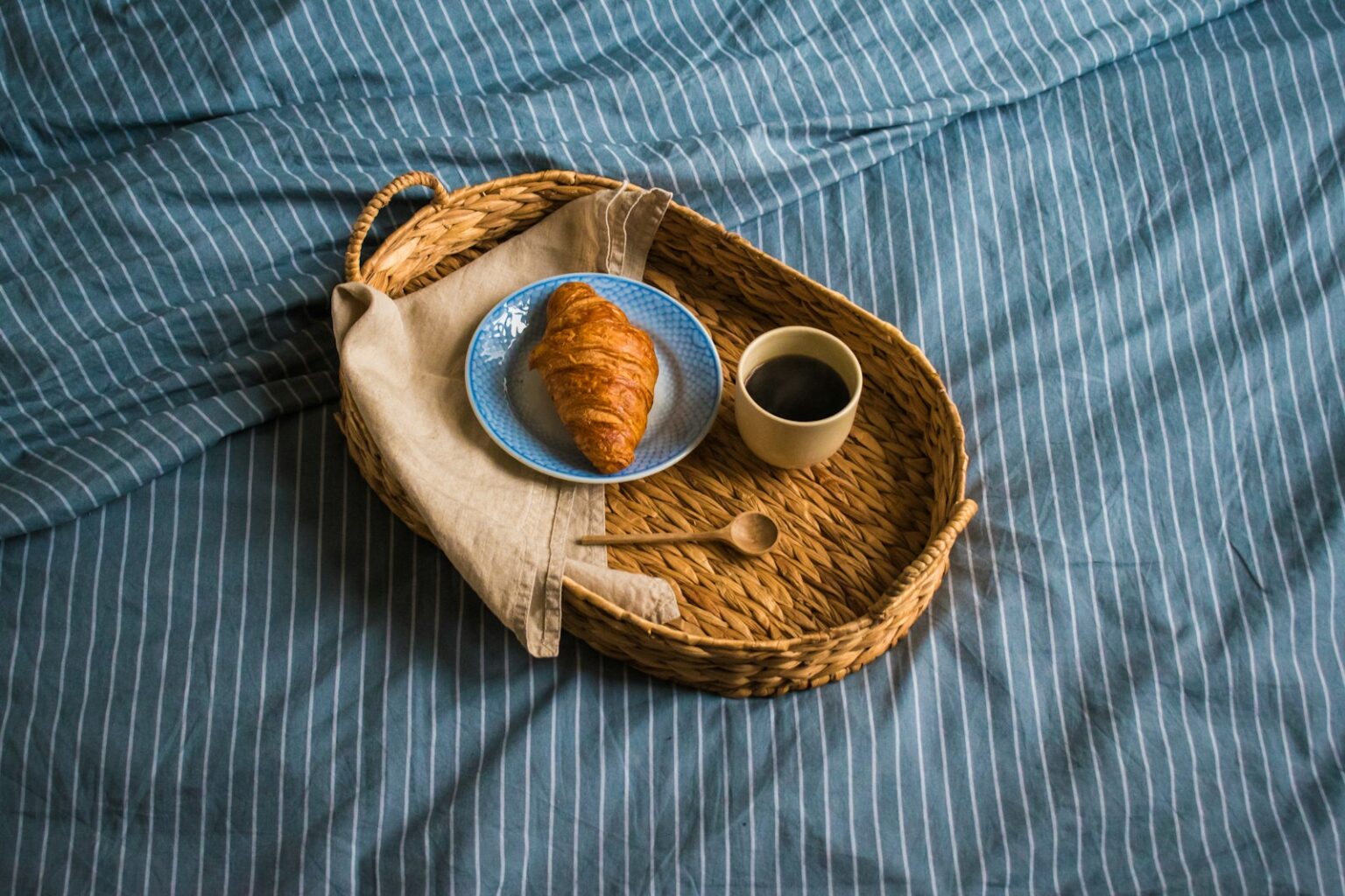 a tray with a croissant and a cup of coffee on it