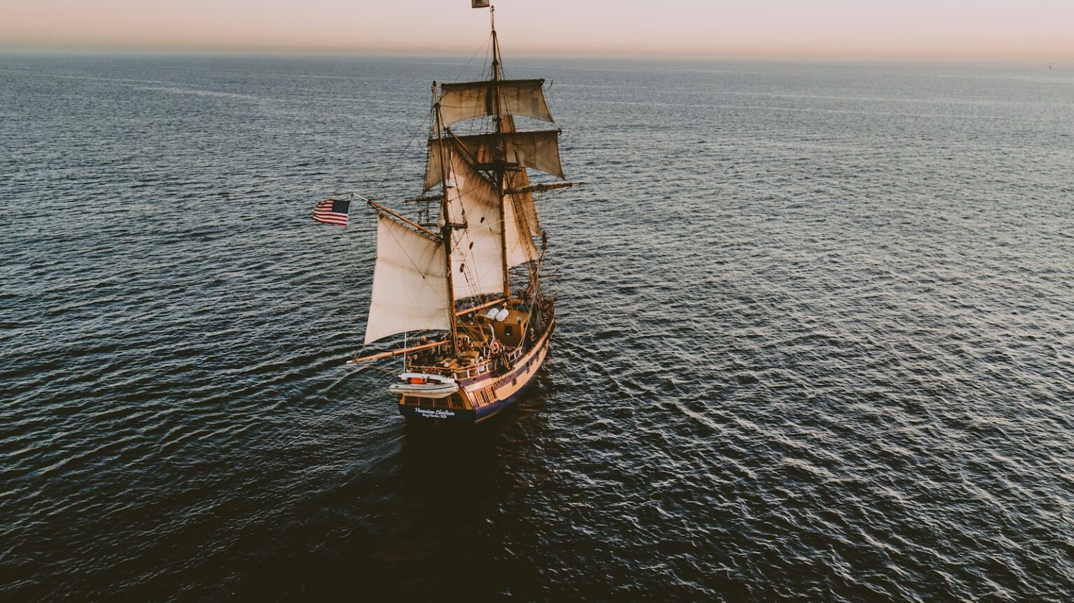 brown sailboat in beach under white sky