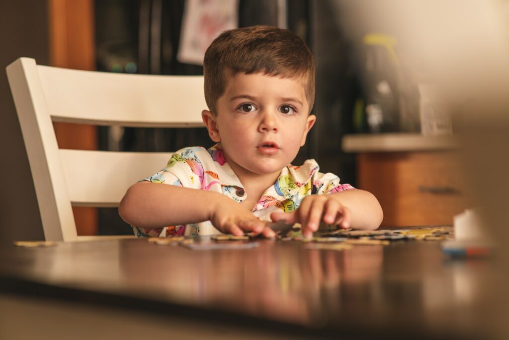 a young boy sitting at a table with a puzzle