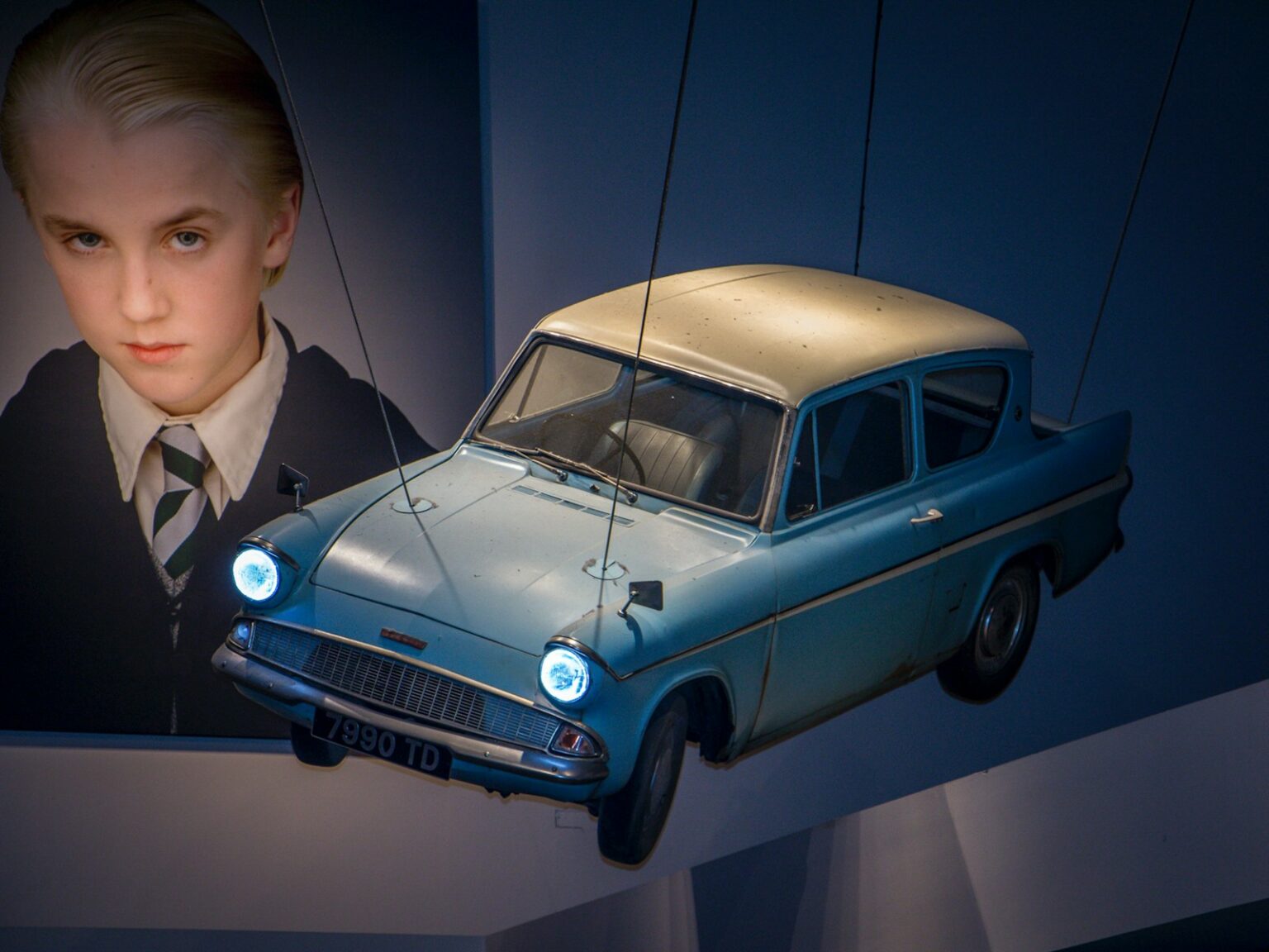 man in black suit jacket standing beside blue car