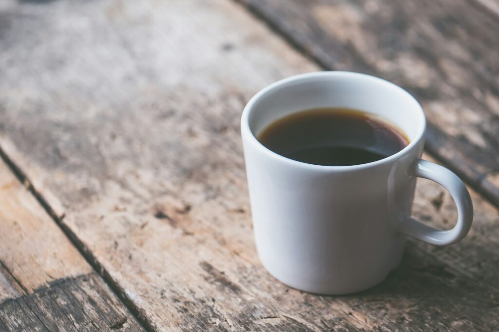 coffee filled white ceramic mug on brown wooden surface