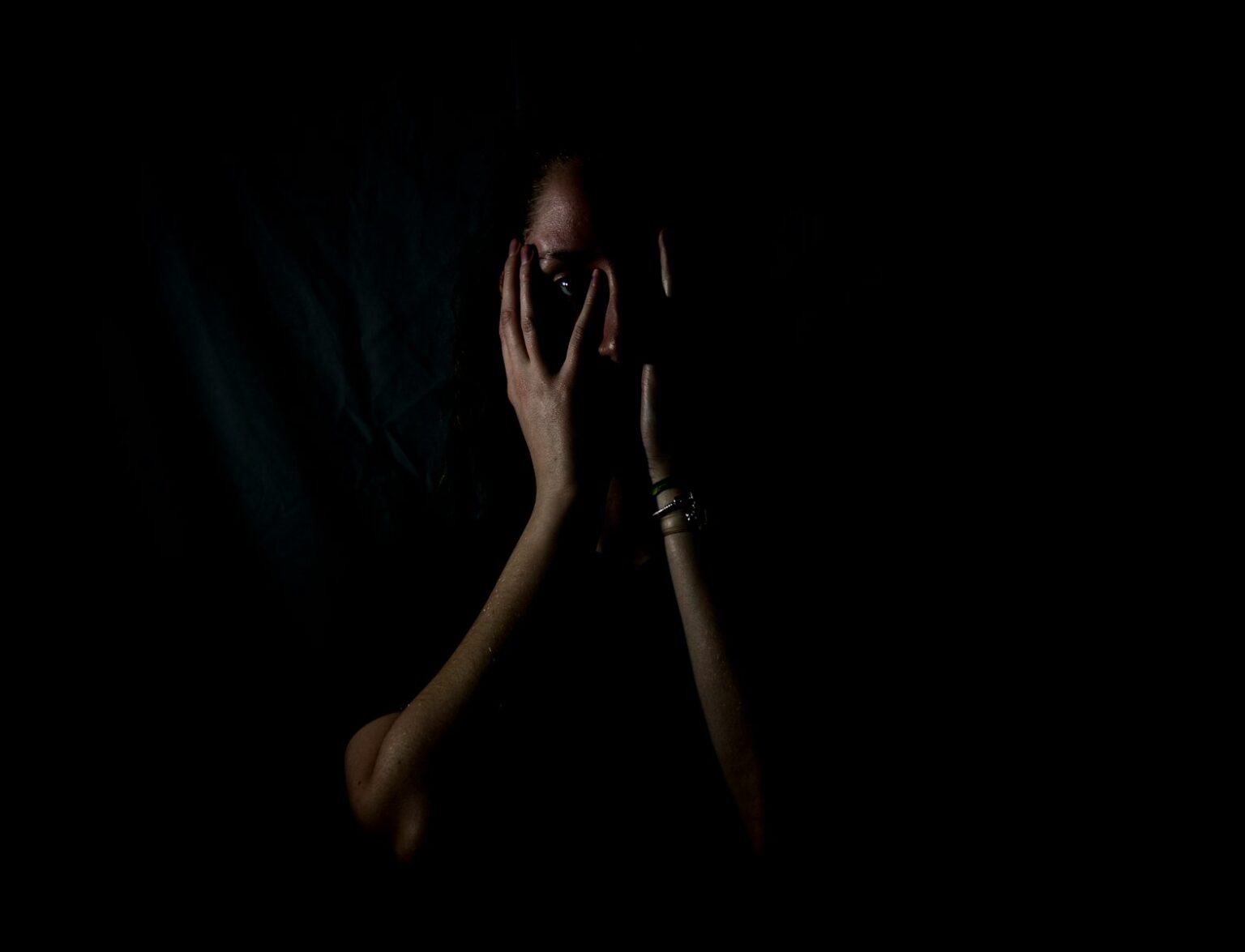 woman holding her face in dark room