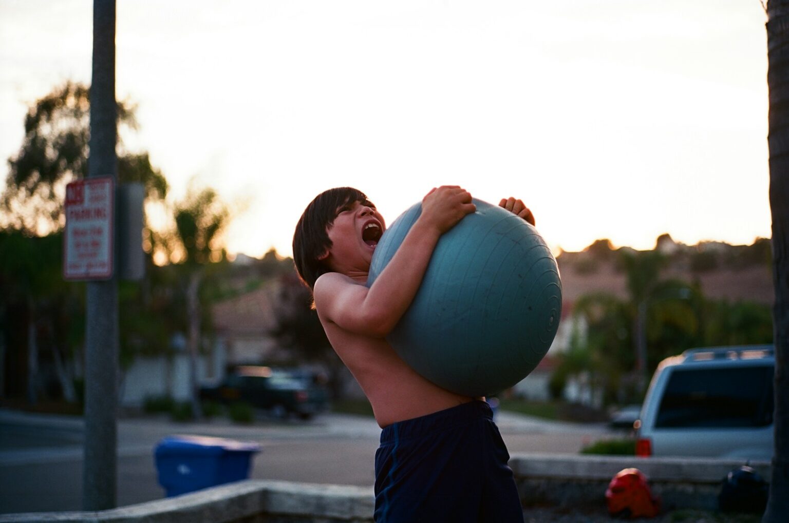 boy's hugging yoga ball while opening mouth