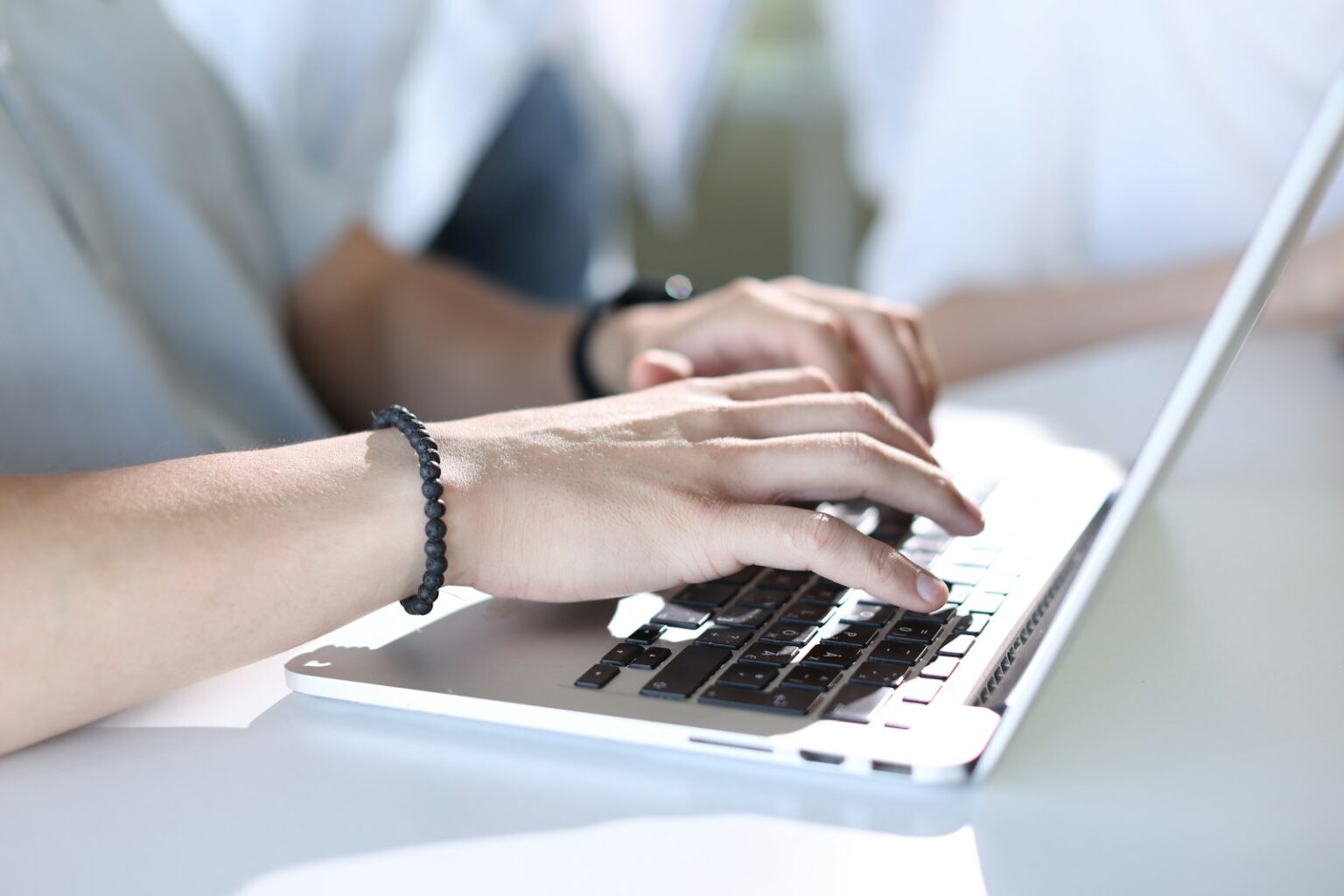 A person typing on a laptop on a table