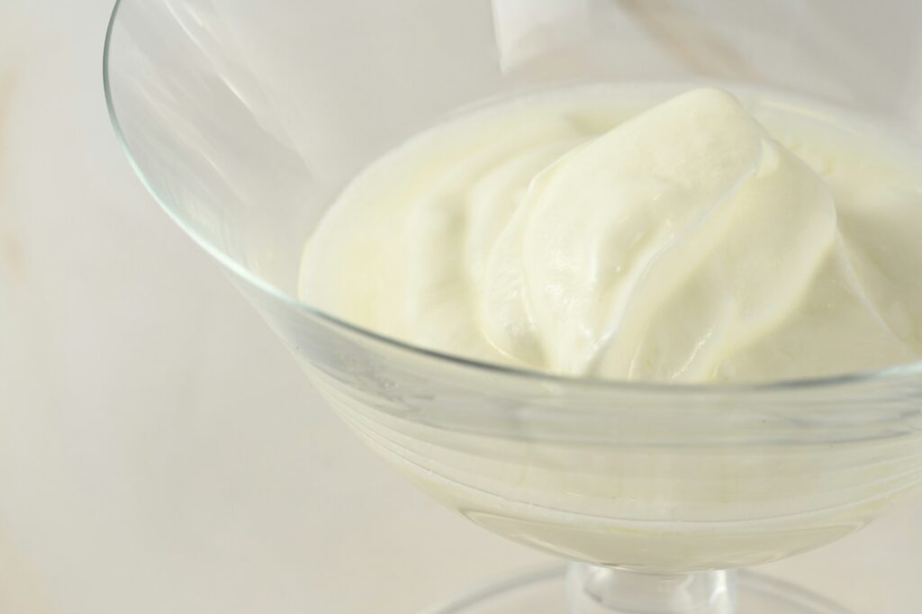 a glass bowl filled with cream on top of a table