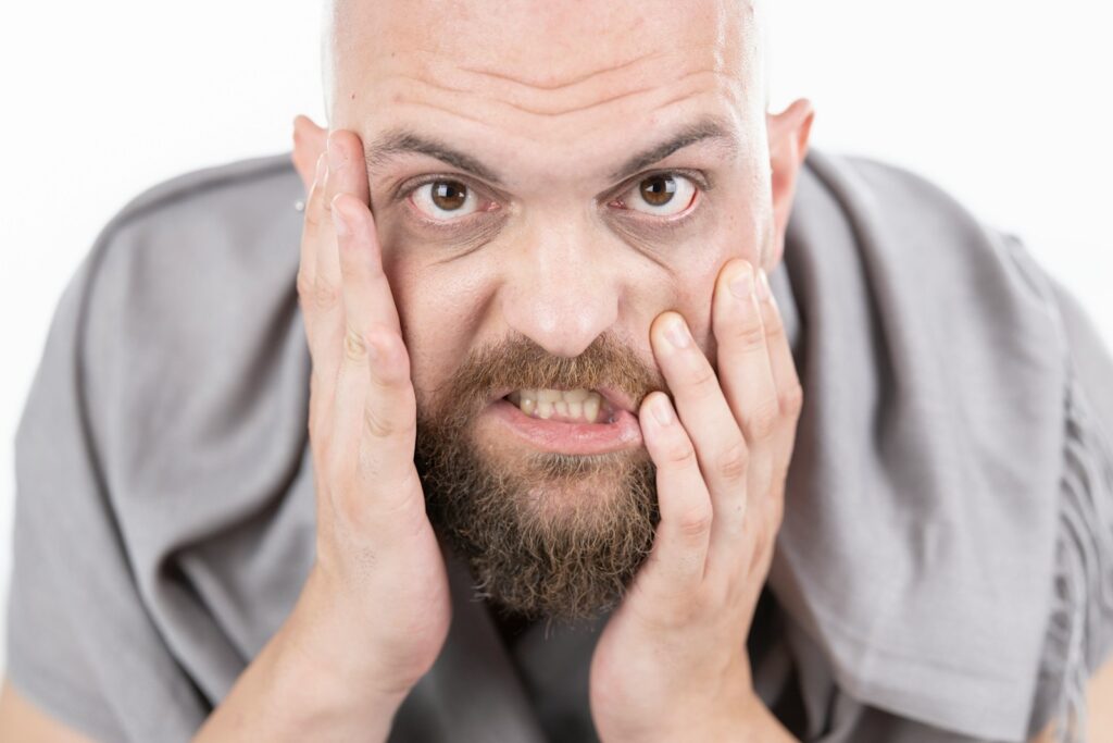 man in gray dress shirt covering his face