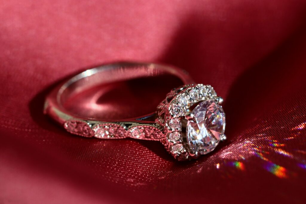 silver diamond ring on red textile