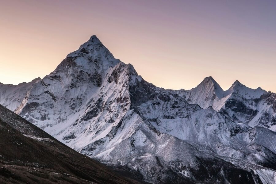a mountain range covered in snow at sunset
