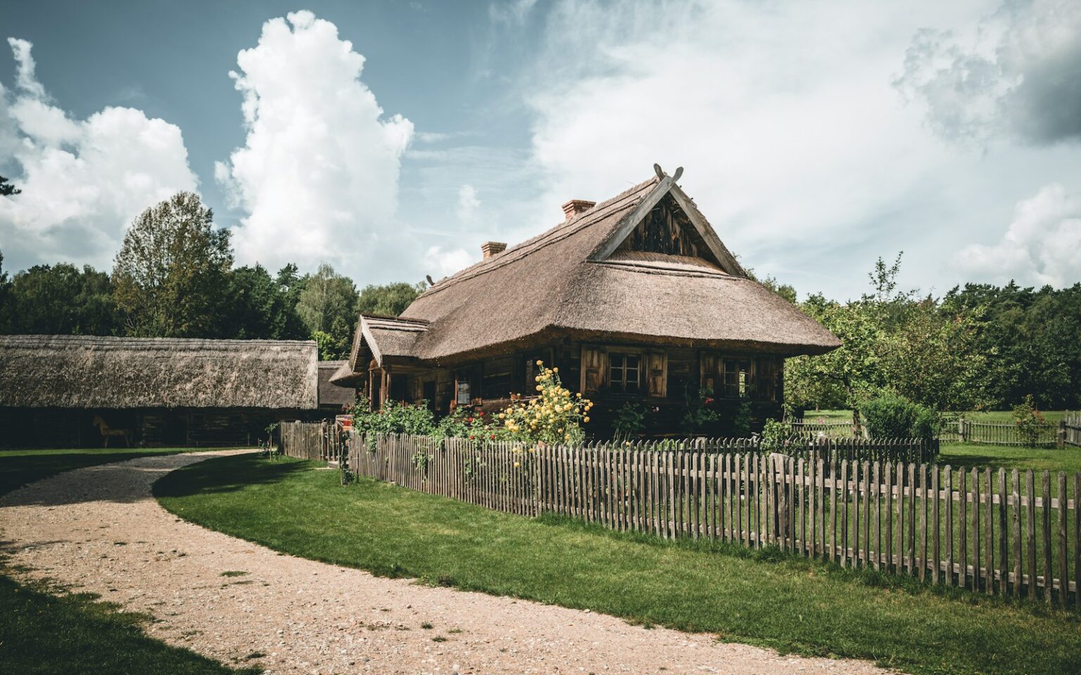 A house with a thatched roof next to a wooden fence