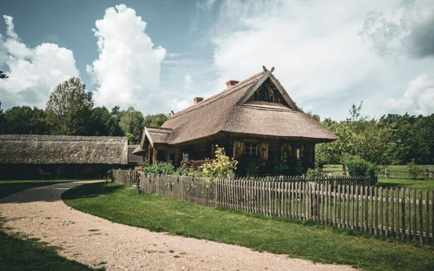 A house with a thatched roof next to a wooden fence