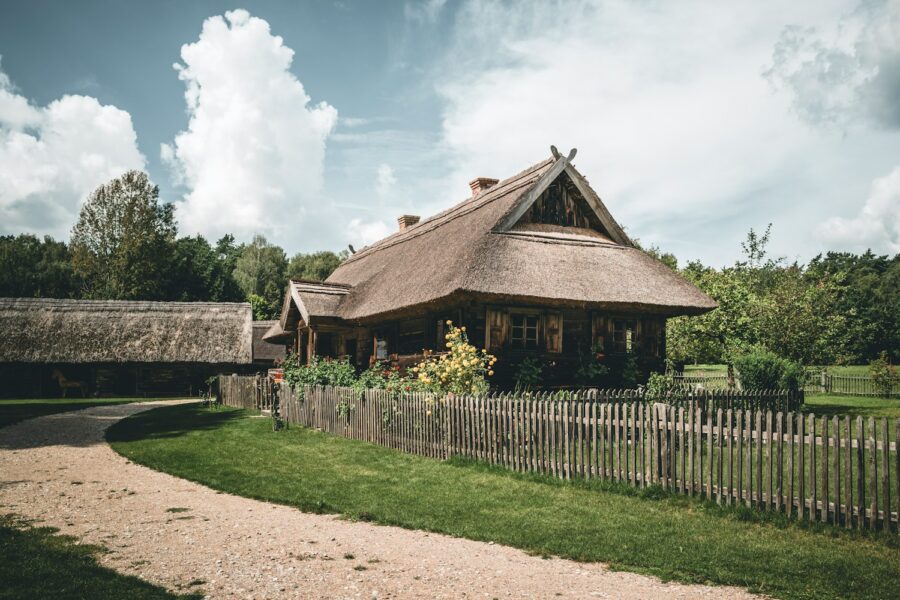 A house with a thatched roof next to a wooden fence