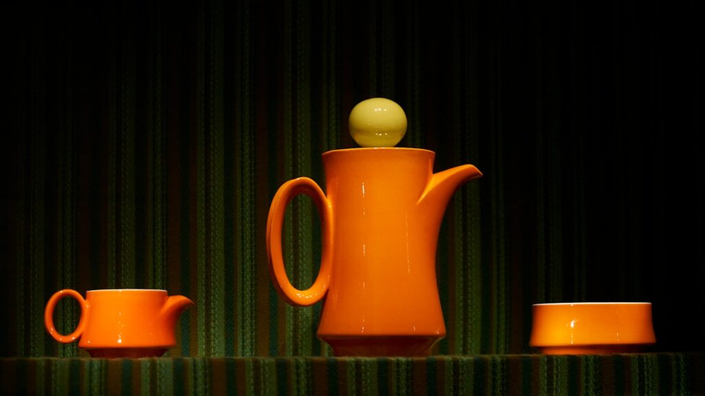 orange ceramic teapot on red textile