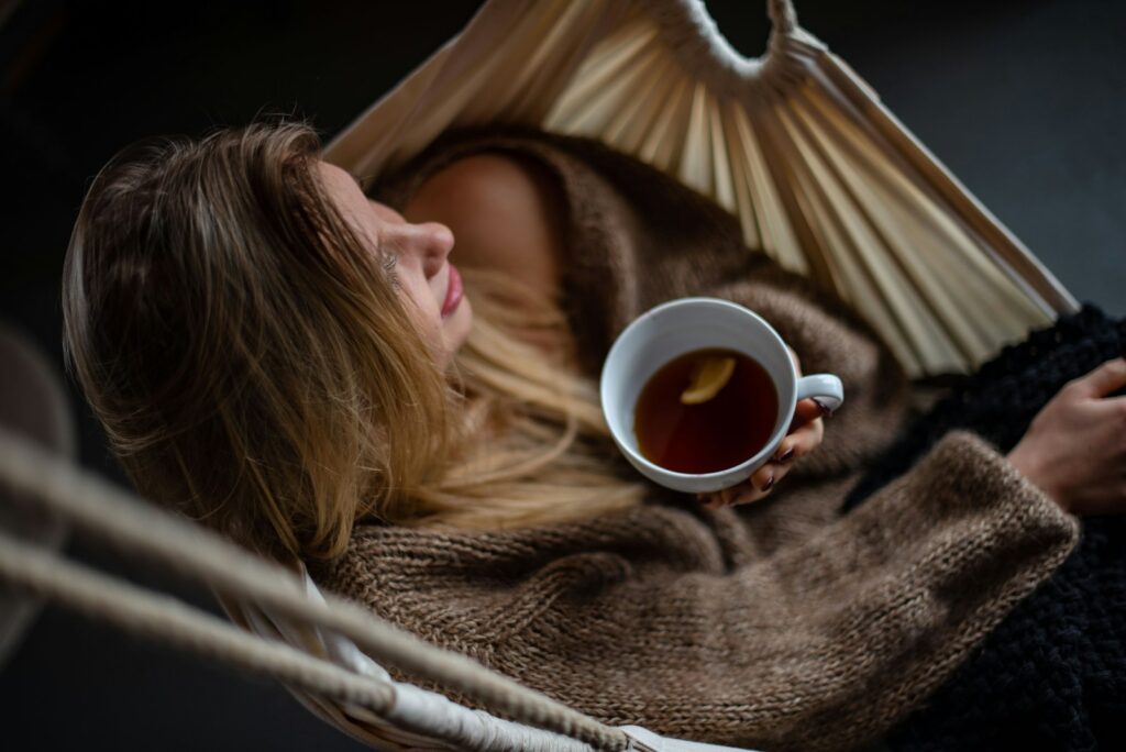 woman on hammock holding cup of coffee