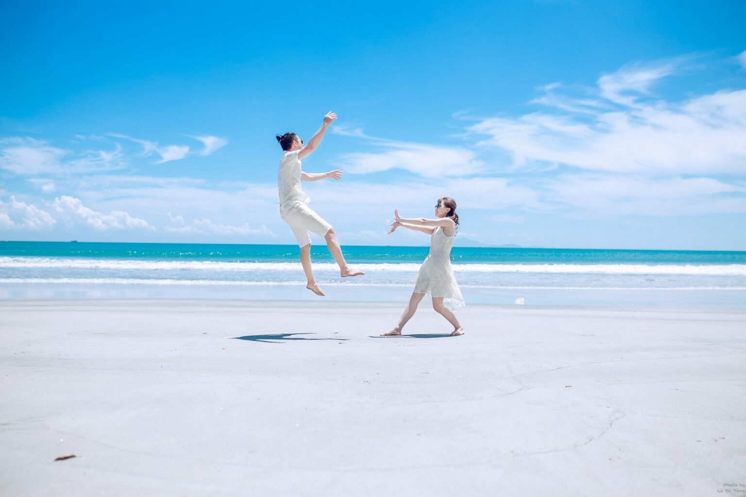 man and woman playing on white sand near seashore during daytime